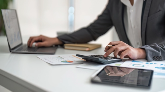 person using a calculator and laptop