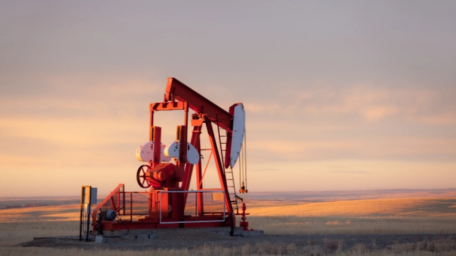 Pump jack in an oil field at sunset