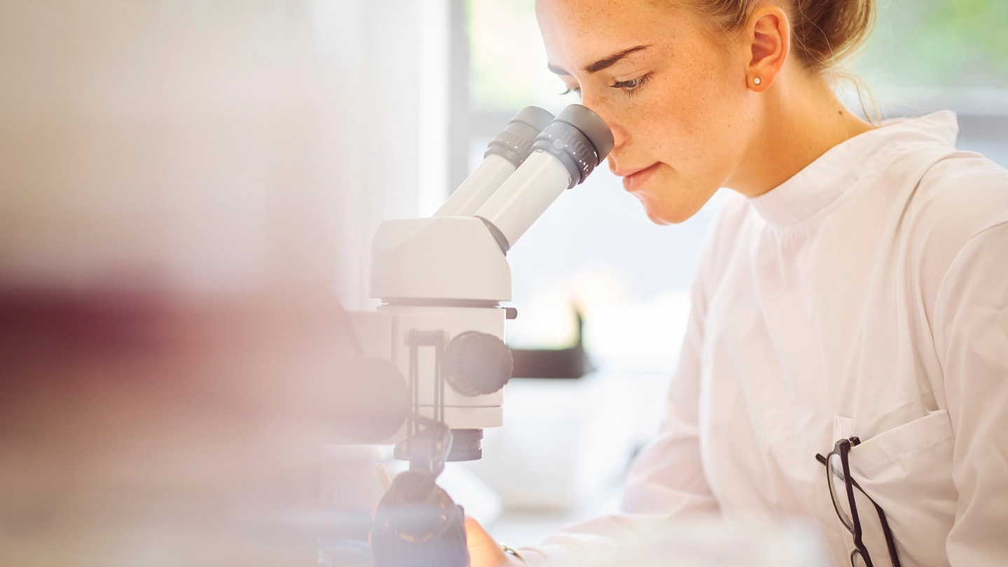 Young female pharmaceutical worker with microscope image